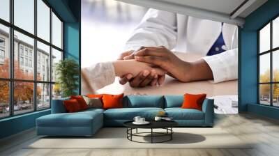 African female doctor hold hand of caucasian woman patient give comfort, express health care sympathy, medical help trust support encourage reassure infertile patient at medical visit, closeup view. Wall mural