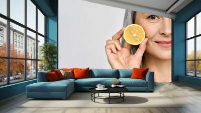 Beauty. Closeup portrait of middle aged beautiful Asian 50s woman with perfect natural makeup holding citrus juicy lemon fruit. Vitamin C cosmetics whitening treatment advertising concept. Copy space. Wall mural