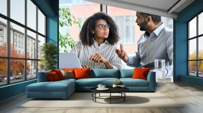 Businessman indian executive manager ceo talking to female African American coworker, using laptop. Diverse multicultural professional partners group discussing business plan at board room meeting. Wall mural