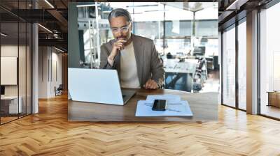 Busy older mature business man executive sitting at desk using laptop. Professional middle aged businessman ceo investor working looking at computer thinking on financial investment in office. Wall mural