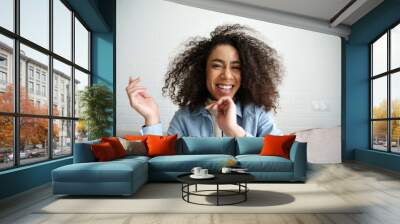 Cheerful african teenage girl blogger talking to camera recording vlog. Happy mixed race young woman laughing making video call at home. Funny social media influencer streaming blog. Webcam view. Wall mural