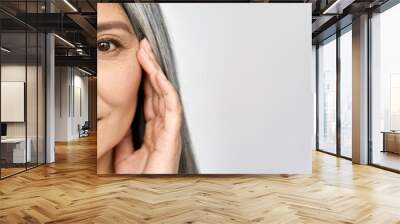 Closeup cut portrait of happy middle aged mature asian woman, senior older 50 year lady looking at camera touching her face isolated on white. Ads of eye lifting anti wrinkle skin care cream. Wall mural