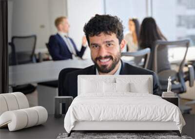 Confident happy young Latin business man worker sitting at office work with laptop looking at camera. Smiling businessman employee at workplace in modern coworking, vertical portrait. Wall mural