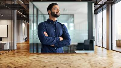 Confident Indian business man leader looking aside standing in office. Smiling professional businessman manager executive, male entrepreneur from India thinking of future career and financial success. Wall mural