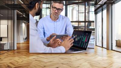 Diverse managers traders analysts discussing financial growth market at desk with laptop with graphs on screen using tablet device. Investors brokers analysing indexes online cryptocurrency stock. Wall mural