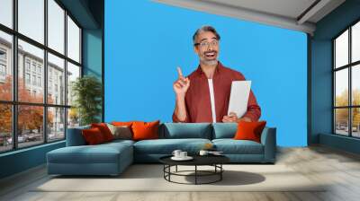 Excited middle aged business man pointing finger holding laptop presenting online product service promo, advertising elearning course sale offer, having new business idea isolated on blue background. Wall mural