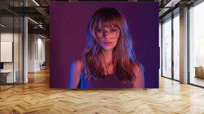 Fashion sexy young woman 20s girl model attractive face blond hairstyle wearing stylish trendy eyewear sunglasses looking at camera at purple violet neon light studio background, closeup portrait Wall mural