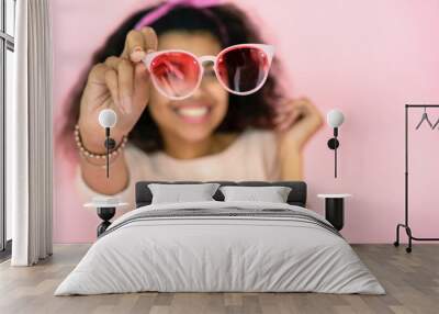 Fashion sunglasses sale, young african girl holding stylish trendy pink glasses Wall mural