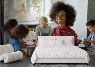 Happy African American junior school kid holding robotic car looking at camera at STEM class. Smiling black child preteen girl posing with robot vehicle. Portrait. Engineering and coding education. Wall mural