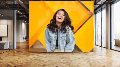 Happy African American young woman wearing denim jacket laughing looking at camera standing near city street building. Smiling positive mixed race teen generation z hipster girl posing outdoor. Wall mural