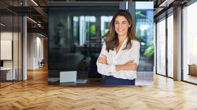 Happy cheerful 45 year old Latin professional mid aged business woman corporate leader, smiling positive mature female executive manager standing in office arms crossed looking at camera, portrait. Wall mural