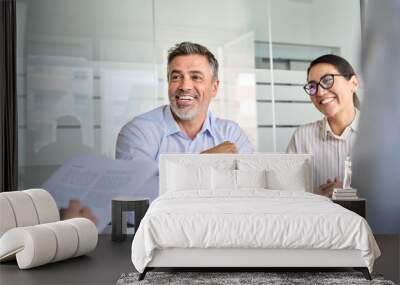 Happy diverse business people international corporate executive team talking at group meeting. Smiling older Latin male manager working with colleagues collaborating at boardroom table. Wall mural