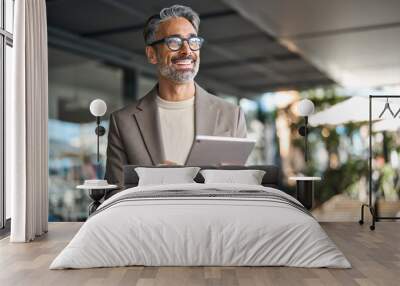 Happy elegant middle aged professional business man financial executive manager using digital tablet. Smiling confident mature businessman holding tab computer technology looking away at copy space. Wall mural