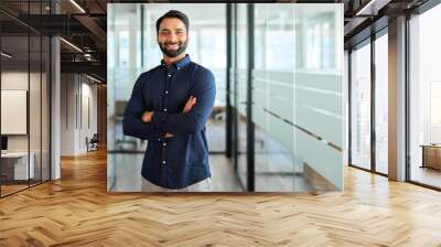 Happy Indian businessman professional leader standing arms crossed in office. Smiling male employee, business man company executive manager, confident eastern entrepreneur at work, portrait. Wall mural