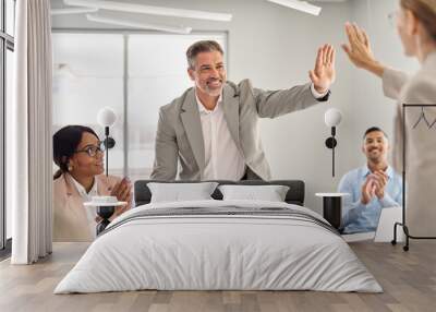 Happy international board executive team leaders partners giving high five celebrating financial success in collaboration, company work achievement over office table at group employees meeting. Wall mural