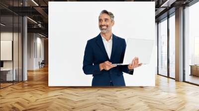 Happy mature business man using laptop standing isolated on white background. Middle aged professional businessman ceo executive wearing suit holding computer working online looking away at copy space Wall mural