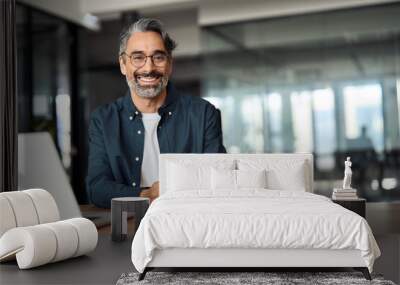 Happy middle aged professional business man, older executive ceo manager, smiling mature entrepreneur wearing glasses and shirt sitting at office desk working on laptop computer. Copy space. Portrait. Wall mural