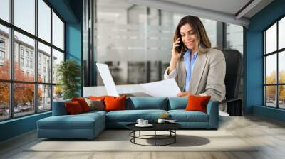 Happy middle aged professional business woman executive making call having conversation at work. Mature female manager or entrepreneur talking on the phone checking document sitting at office desk. Wall mural