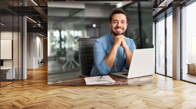 Happy professional business man company employee, young entrepreneur, smiling latin businessman working on laptop computer technology looking at camera working in office sitting at desk, portrait. Wall mural