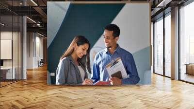 Happy smiling international business team people two colleagues talking standing in office. Diverse workers discussing corporate teamwork marketing plan sharing ideas working together. Vertical shot. Wall mural