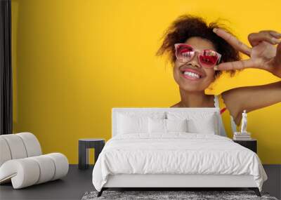 Happy young african woman hold drink wear glasses laugh look at camera, cheerful black teen girl enjoy summer cocktail isolated on yellow studio background, banner design close up portrait copy space Wall mural