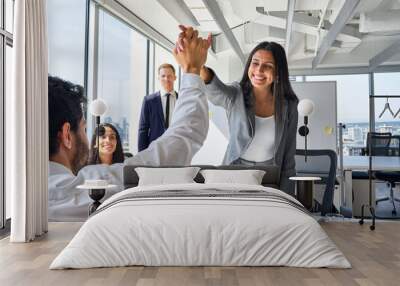 Happy young Indian woman worker giving male colleague high five celebrating good team work results, financial success in professional teamwork at diverse coworkers group office meeting. Wall mural