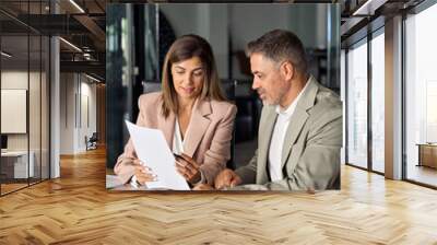 Mature business woman manager holding legal documents consulting client at office meeting, two professional executives experts discussing financial accounting papers working together. Vertical. Wall mural