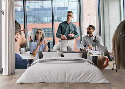 Mature caucasian ceo businessman leader mentor discussing project research financial report results with multicultural professionals project managers, diverse coworkers team in boardroom at meeting. Wall mural