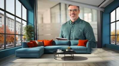 Older smiling business man holding tablet standing in office. Middle aged happy businessman manager investor using tab computer, mature male executive looking at camera at work. Portrait. Wall mural