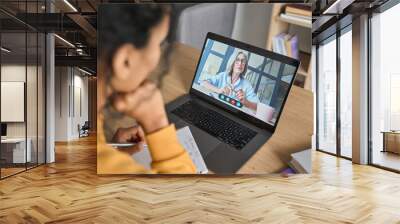 Over shoulder view of female adult student having virtual meeting online call educational webinar chatting with senior teacher at home office writing notes. Video e learning conference call on pc. Wall mural