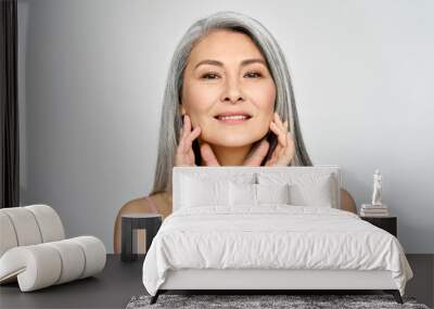 Portrait of gorgeous beautiful middle aged mature asian woman, senior older 50 year lady looking at camera touching her face isolated on white. Ads of lifting anti wrinkle skin care, spa. Wall mural