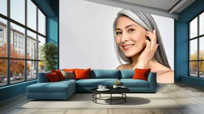 Portrait of gorgeous happy middle aged mature asian woman, senior older 50 year lady looking at camera touching her face isolated on white. Ads of lifting anti wrinkle skin care, spa. Copy space. Wall mural