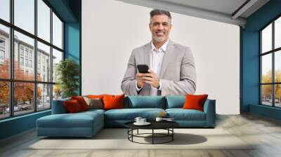 Portrait of happy middle aged business man wearing suit using mobile cell phone looking at camera isolated on white. Smiling older businessman holding cellphone using banking finance app on smartphone Wall mural