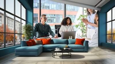 Senior older female executive ceo and happy multicultural business people discuss corporate project at boardroom table. Smiling diverse corporate team working together in modern meeting room office. Wall mural