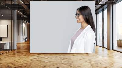 Side profile view of happy smiling young adult indian business lady in white formal wear. Cheerful businesswoman wear suit woman looking away and standing isolated on grey background copy space Wall mural