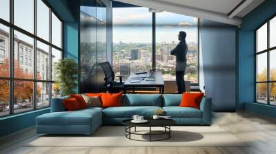 Silhouette of indian confident successful businessman thinking imagining future corporate financial career standing at office near window of high floor building with city view on big urban center. Wall mural