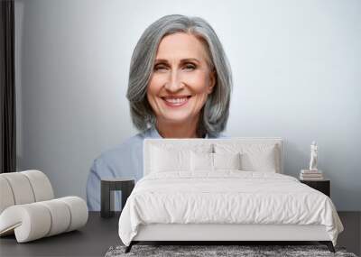 Smiling beautiful mature business woman standing isolated on white background. Older senior businesswoman, 60s grey haired lady professional coach looking at camera, close up face headshot portrait. Wall mural