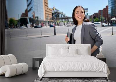 Smiling confident beautiful Asian young woman entrepreneur, professional businesswoman manager or saleswoman wearing business suit holding tablet standing on city street. Wall mural