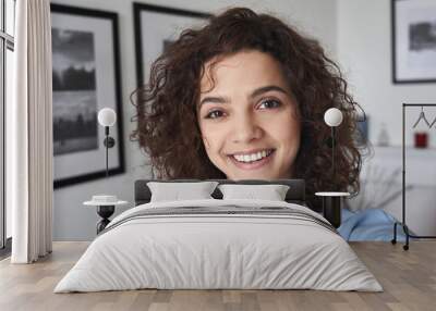 Smiling cute cheerful young pretty hispanic latin woman looking at camera standing alone at home. Happy positive beautiful 20s girl female model posing indoors, close up face headshot portrait. Wall mural