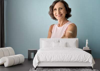 smiling healthy mature older senior happy woman showing bandage on arm after getting vaccination. va Wall mural