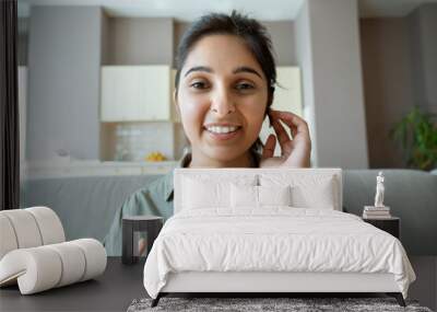 Smiling indian woman professional online teacher, telesales agent, remote tutor or call center operator wearing headset look at webcam conference video call center at home office. Headshot portrait. Wall mural