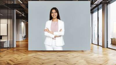 Smiling indian young businesswoman wear white suit looking at camera isolated on grey studio background, happy attractive confident hindu business lady professional with arms crossed portrait Wall mural