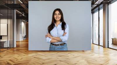 Smiling indian young woman sales professional arms crossed looking at camera isolated on grey blank studio background copy space, happy female student saleswoman girl posing on gray wall, portrait Wall mural