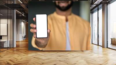 Smiling man holding cell phone in hand showing blank white mock up phone screen advertising mobile applications online tech on smartphone. Mockup cellphone display advertising template design. Wall mural