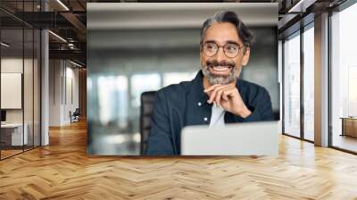 Smiling mature business man executive wearing shirt sitting at desk using laptop. Happy busy professional middle aged Indian businessman investor working on computer looking away in office. Copy space Wall mural