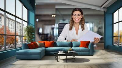 Smiling mature business woman hr holding cv document at job interview. Happy mid aged professional banking manager or lawyer consulting client sitting at workplace in corporate office meeting. Wall mural