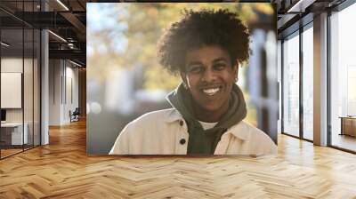 Smiling positive young African American guy model standing at big city sunny street. Stylish ethnic hipster gen z teenager feeling happy looking at camera outdoors in park, Close up portrait. Wall mural