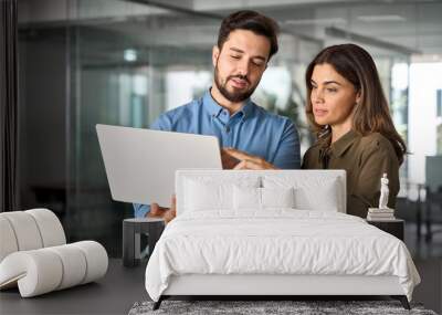 Two busy professional business people working in office with computer. Middle aged female executive manager talking to male colleague having conversation showing software online solution on laptop. Wall mural