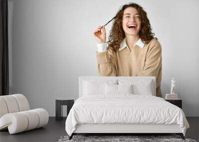 Young adult smiling beautiful positive woman model, joyful pretty cheerful cute curly girl student looking at camera laughing playing with curly hair, standing isolated at white background, portrait. Wall mural