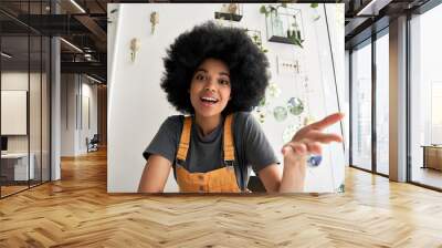 Young African American hipster woman with Afro hair looking at webcam talking to camera with friend online sitting at cafe table making video call, virtual chat, recording blog, headshot portrait. Wall mural